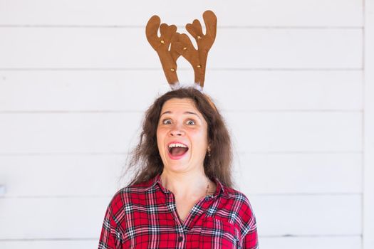 Woman with Christmas deer horns on white background.