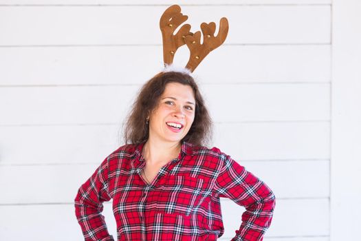 people, clothing and christmas concept - funny santa girl in deer horns on her head on white background.