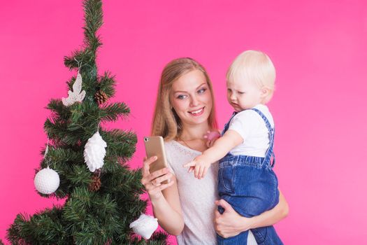Mother and little daughter taking a selfie near Christmas tree.
