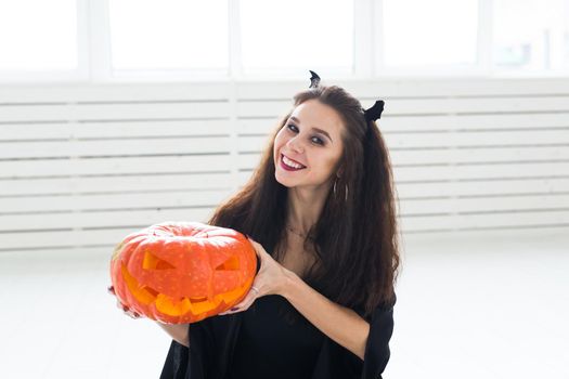 Halloween and masquerade concept - Beautiful young woman posing with Pumpkin Jack-o'-lantern