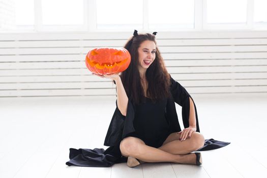 Cute woman in halloween style clothes with pumpkin in hands.