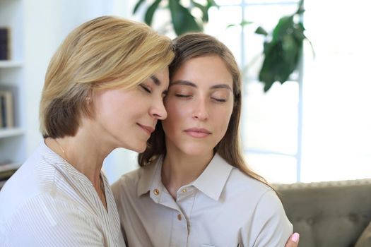 Middle aged mother and daughter talking on sofa in living room