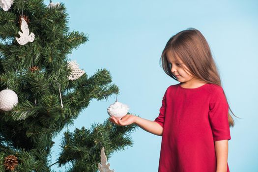 Little girl with christmas tree on blue background.