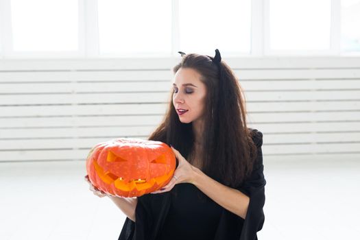 Cute woman in halloween style clothes with pumpkin in hands.