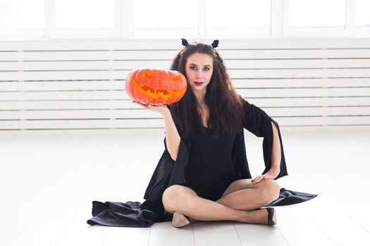 Halloween and masquerade concept - Beautiful young woman posing with Pumpkin Jack-o'-lantern