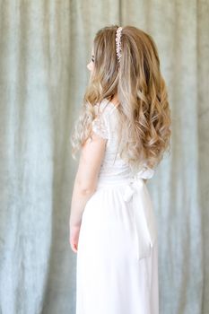 Back view of blonde bride wearing white dress at photo studio. Concept of wedding fashion and fiancee.