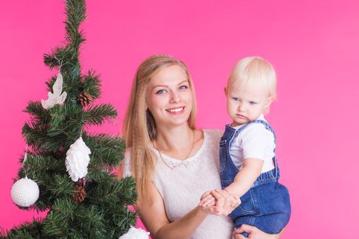 Christmas and holiday concept - Portrait of smiling woman with her little daughter decorating Christmas tree.