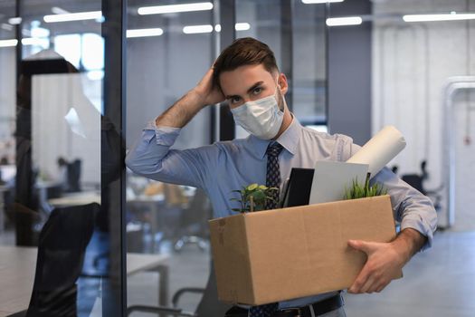 Dismissal employee in an epidemic coronavirus. Dismissed worker going from the office with his office supplies