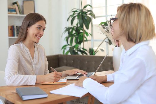 Cheerful female doctor psychologist shaking grateful patient hands after having a consultation meeting