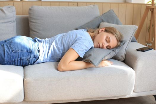 Portrait of young woman lying on couch and sleeping
