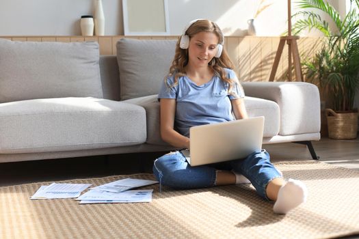 Image of pretty woman working with laptop while sitting on floor at home
