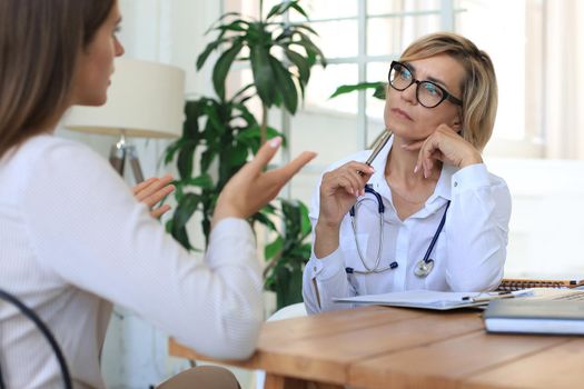 Middle aged female doctor therapist in consultation with patient in office