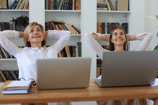 Calm smiling businesswoman relaxing at comfortable office chair hands behind head, happy woman resting in office satisfied after work done, enjoying break with eyes closed, peace of mind, no stress