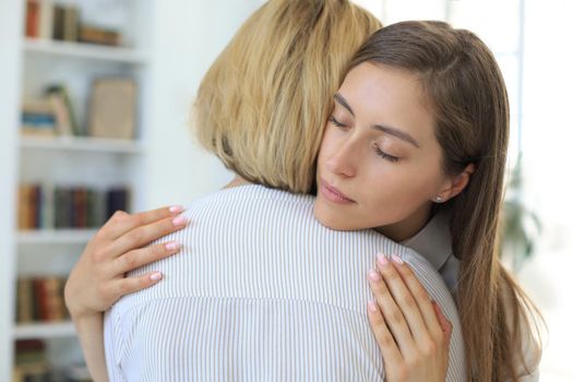 Concerned middle aged mother hugging her adult daughter, listen her anxieties