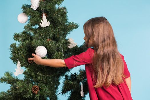 Christmas, childhood and people concept - little girl decorating the christmas tree.
