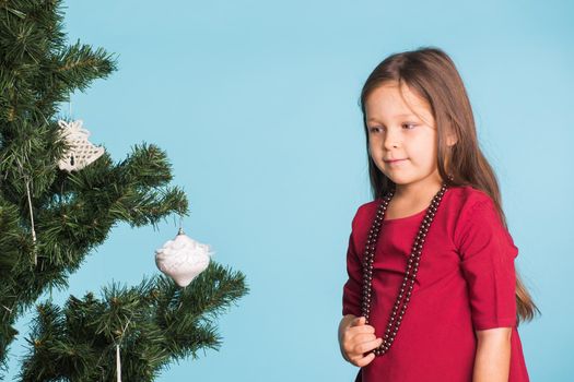 Little girl with christmas tree on blue background.