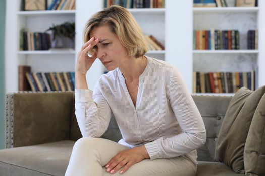 Worried middle aged woman sitting on a sofa in the living room