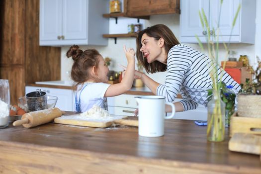 Playful little girl cooking at kitchen with her loving mother