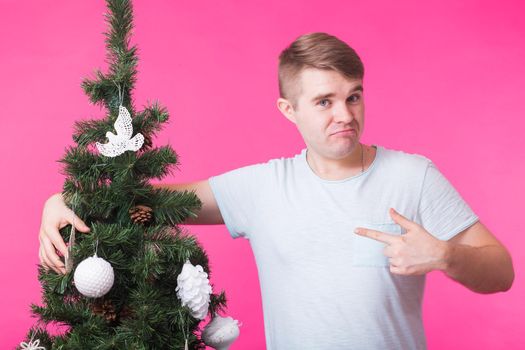 Holidays and people concept - Happy man with christmas tree on pink background.