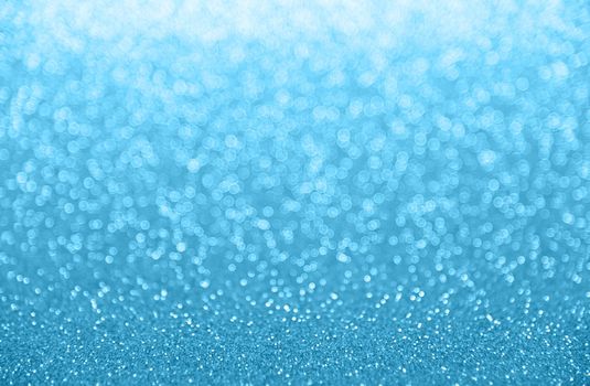 Abstract background of cold winter blue bokeh defocused blurred lights and glitter sparkles