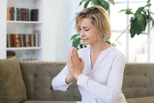 Middle aged woman praying, eyes opened, looking up, hoping for best, asking for forgiveness