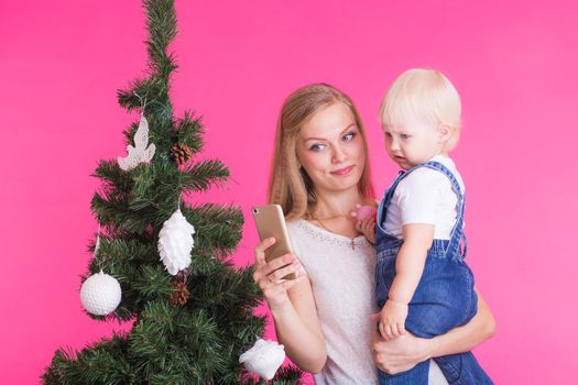 Mother and little daughter taking a selfie near Christmas tree.