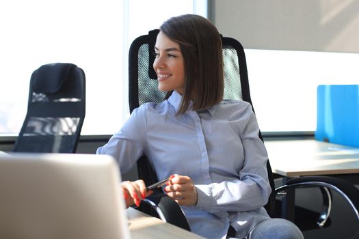 Smiling modern woman is thinking about business while working in the office