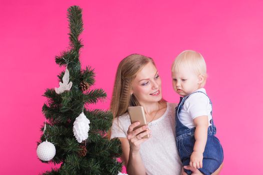 Mother and little daughter taking a selfie near Christmas tree.