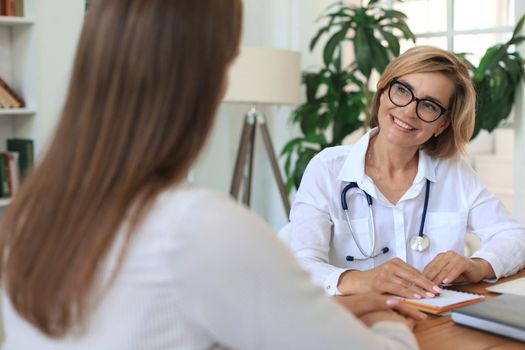 Middle aged female doctor therapist in consultation with patient in office