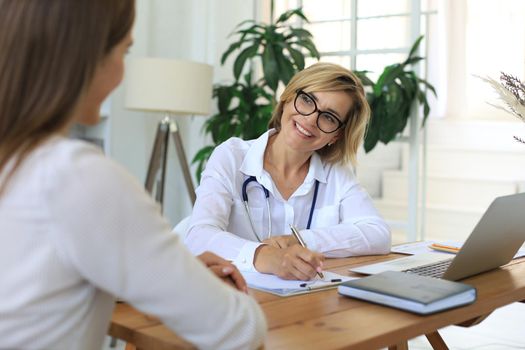 Middle aged female doctor therapist in consultation with patient in office
