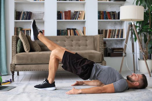 Handsome man doing sport exercise at home during quarantine. Concept of healthy life