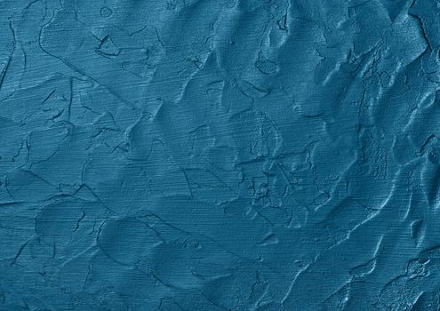 Close up vivid blue abstract background texture of uneven grunge surface with brushstrokes of plaster and paint