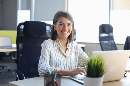 Beautiful business woman in smart casual wear working on laptop in the office.