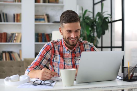 Happy young business man is analizing financial documents from home during self isolation