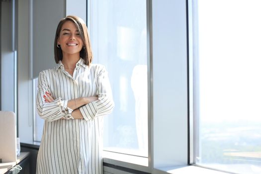 Attractive business woman looking at camera while standing in the office