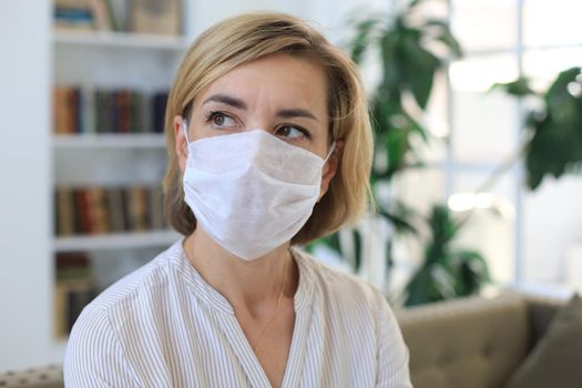 Middle aged woman in medical mask at home during epidemic situation