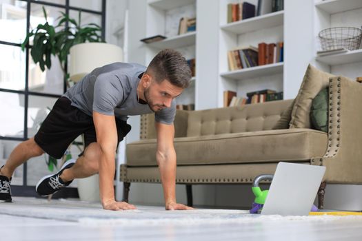 Handsome man doing sport exercise at home during quarantine. Concept of healthy life