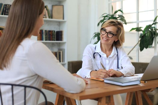 Middle aged female doctor therapist in consultation with patient in office