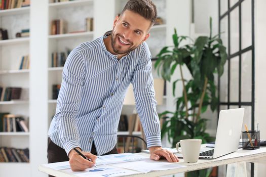Young modern business man analyzing data using laptop while working in the office