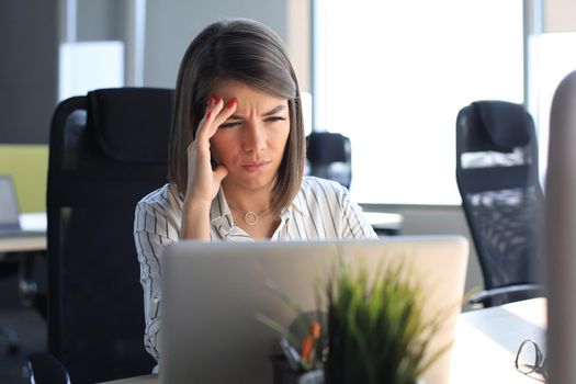 Frustrated business woman looking exhausted while sitting at her working place