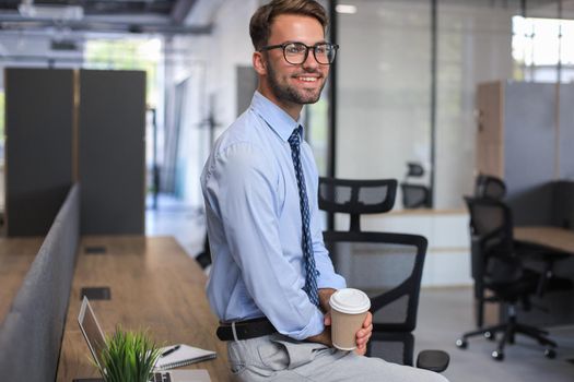 Portrait of young man sitting at his desk in the office.