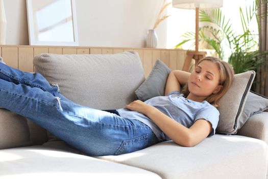 Portrait of young woman lying on couch and sleeping
