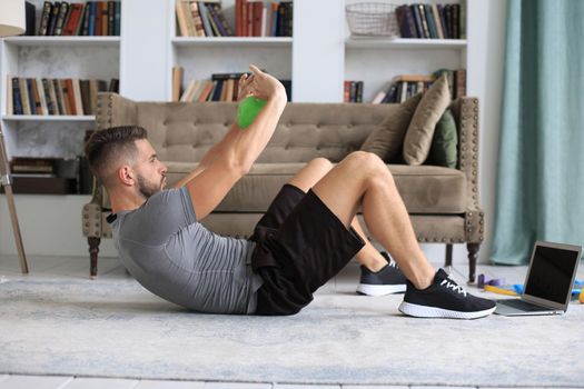 Handsome man doing sport exercise with kettlebell at home. Concept of healthy life