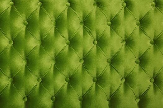 Green velvet capitone textile background, retro Chesterfield style checkered soft tufted fabric furniture diamond pattern decoration with buttons, close up