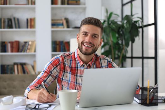 Happy young business man is analizing financial documents from home during self isolation