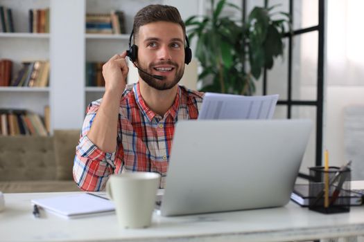 Concentrated young freelancer businessman using laptop for video conferance, working remotely online at home