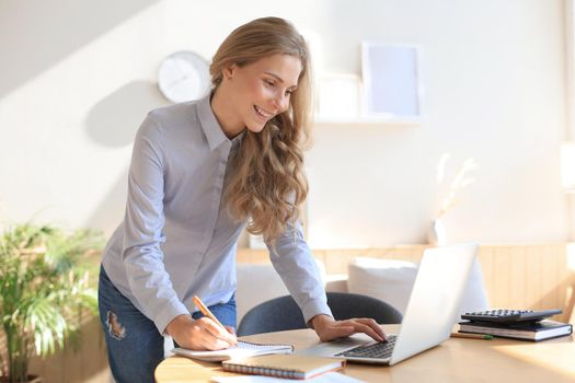 Young business woman standing in her home office reading notes