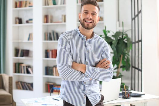 Portrait of happy businessman with arms crossed standing in office