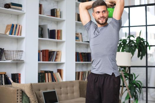 Handsome man doing sport exercise with kettlebell at home. Concept of healthy life