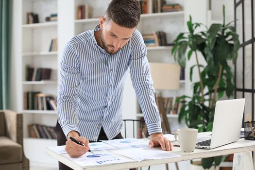 Young modern business man analyzing data using laptop while working in the office
